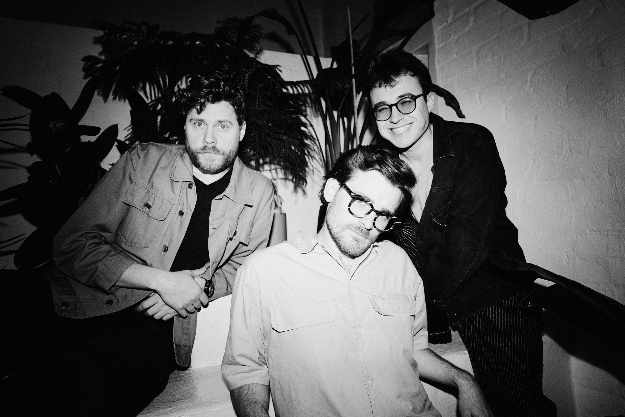 Parzhuber Trio, band photo, three musicians close together in front of houseplants and a brick wall, flash, black and white, 2025, photographed by Kilian Amrehn