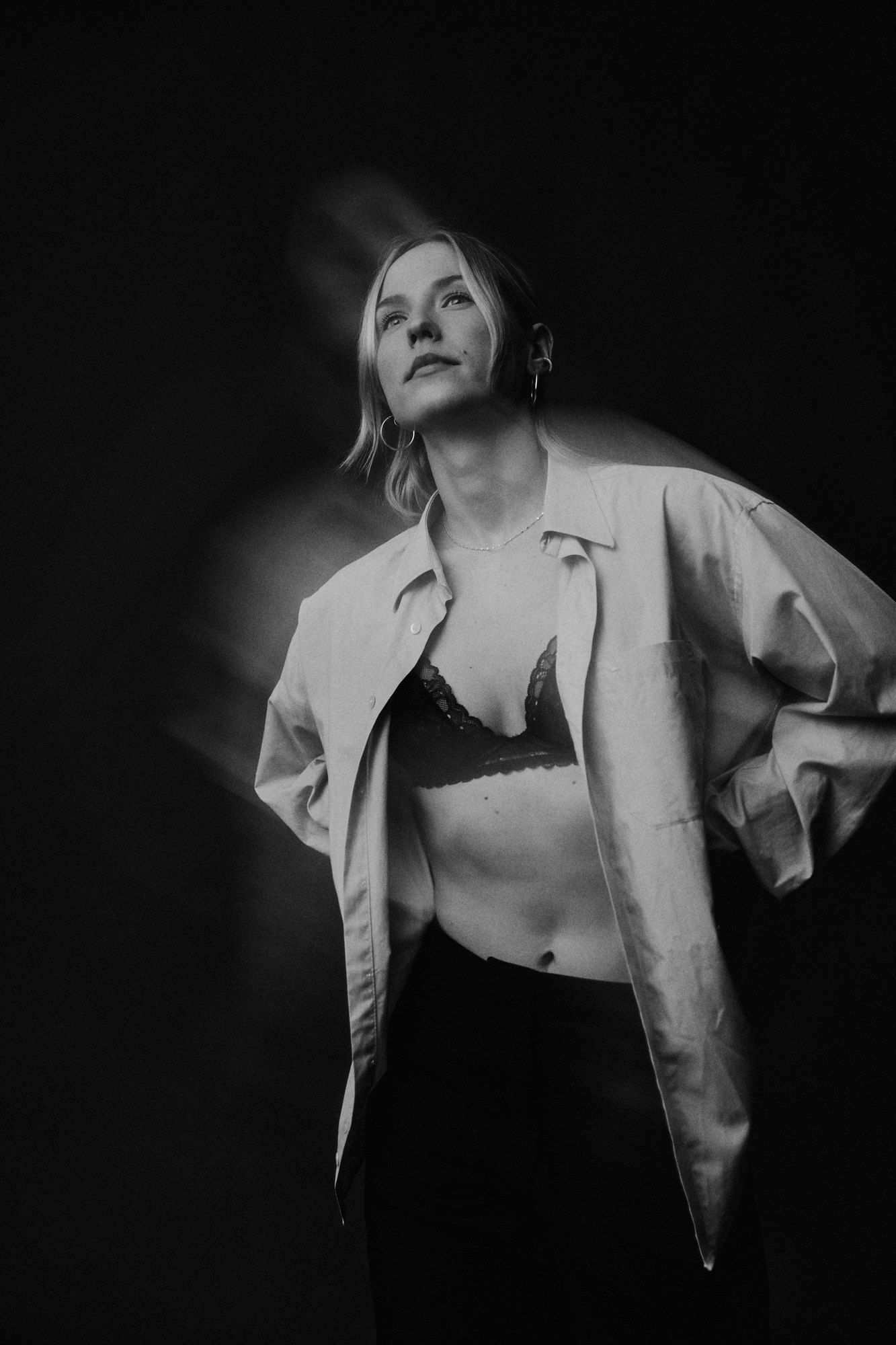 Paula, DJ, in an open white shirt over a lace bralette, looking up, double exposure, black and white, 2026, photographed by Kilian Amrehn