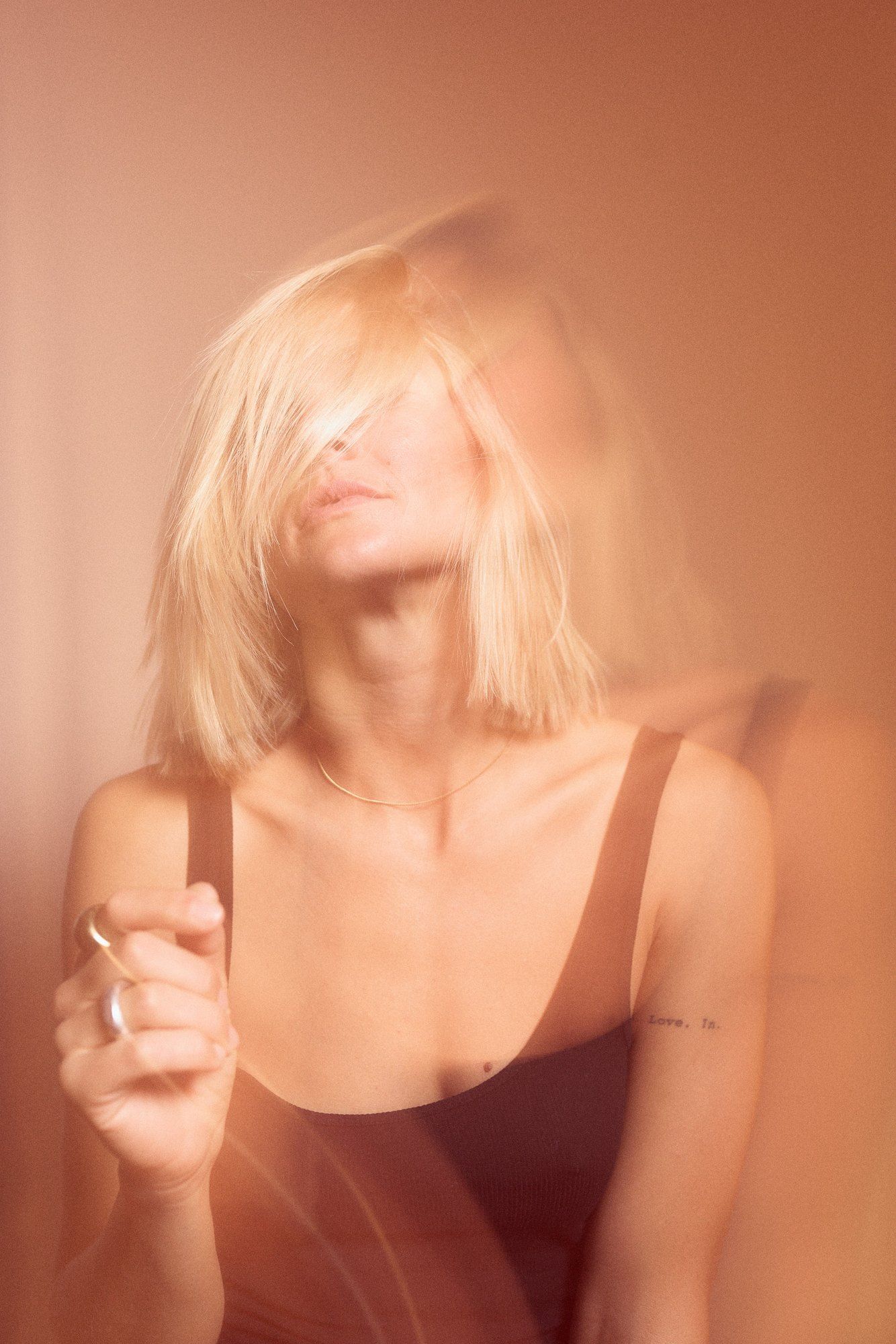 Pia Stutzenstein, actress, blonde hair across her face in motion blur, warm peach light, 2022, photographed by Kilian Amrehn