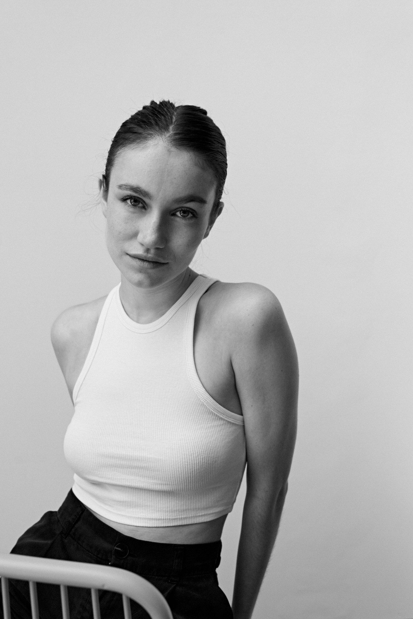 Salomé, actress, in a white tank top sitting on a chair, leaning slightly forward, black and white, 2024, photographed by Kilian Amrehn