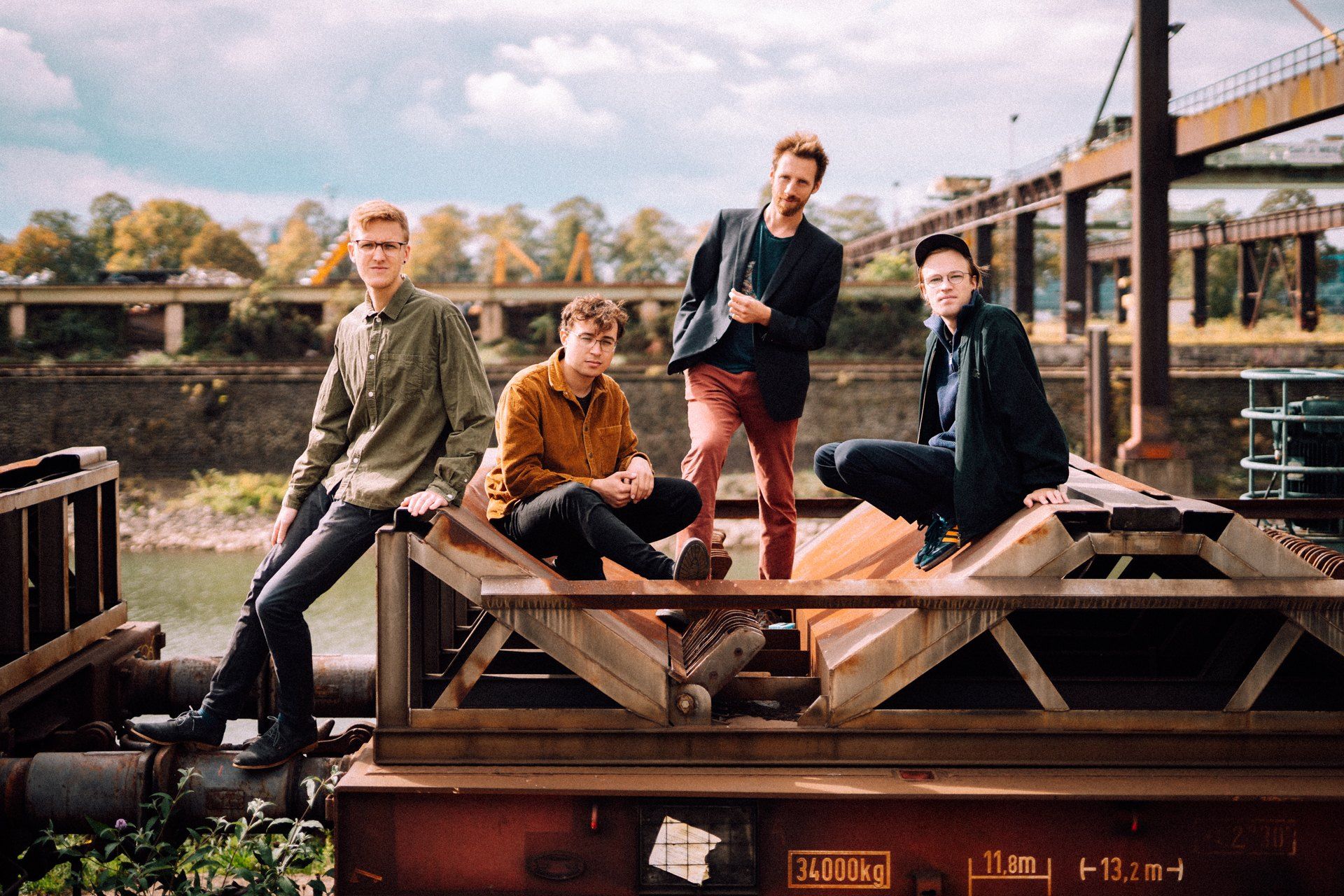 Simon und Quartett, band photo, four musicians on a rusty freight wagon at a harbour, cranes and autumn light, 2019, photographed by Kilian Amrehn