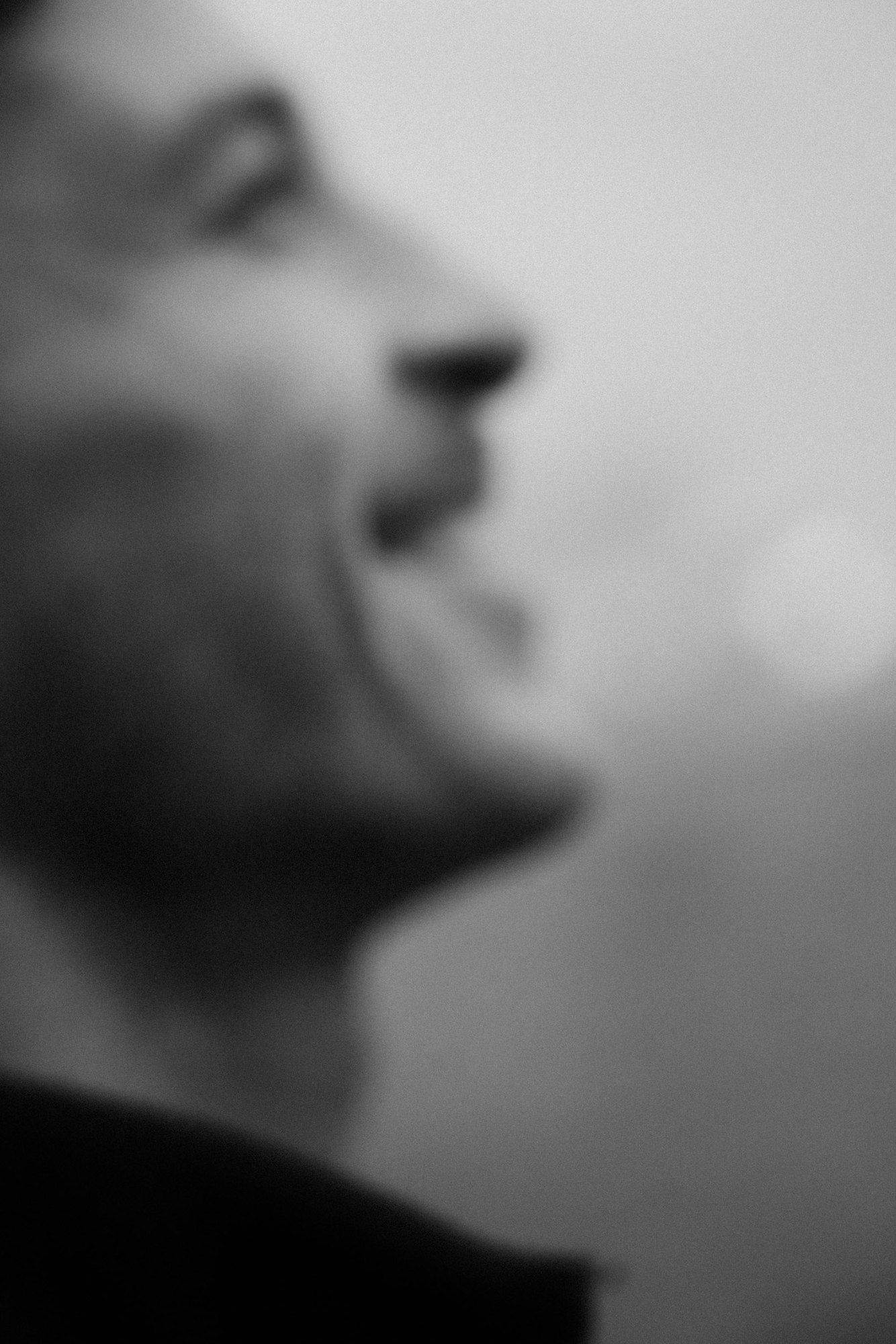 Slavko Popadić in profile looking upward, soft focus in the foreground against a bright background, black and white, 2021, photographed by Kilian Amrehn