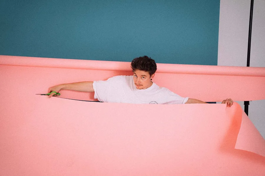 Man cuts his way through a pink paper backdrop with scissors in the studio, analogue, flash by Kilian Amrehn