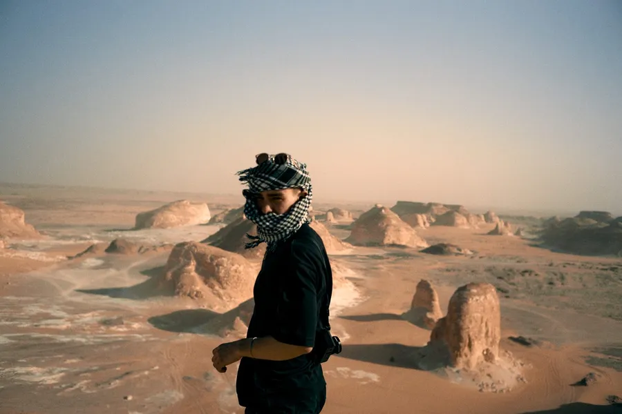 Masked man in morning haze above a desert of white chalk rock formations, flash by Kilian Amrehn