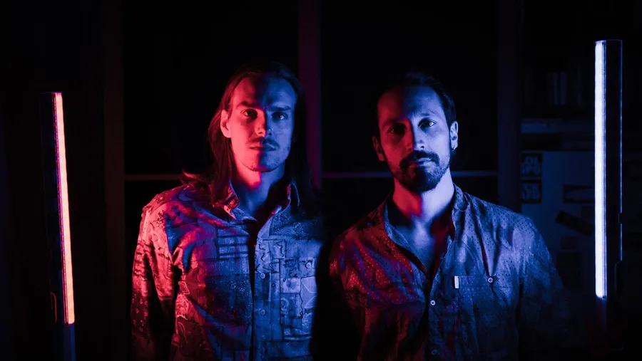 Two men in patterned shirts lit by red and blue neon tube lights, flash by Kilian Amrehn