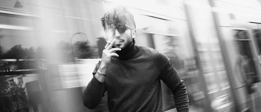 Man in sunglasses smokes in front of a passing train, motion blur, black and white, flash by Kilian Amrehn