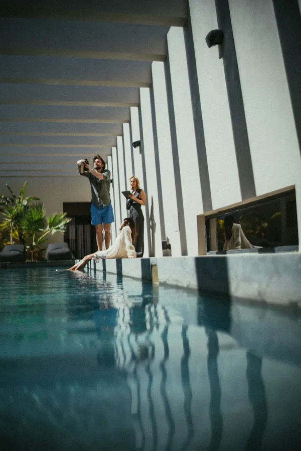 Photographers at the edge of an indoor pool between white concrete pillars, flash by Kilian Amrehn