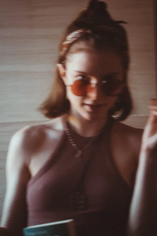 Woman with tinted sunglasses and a hair bun in soft, blurry light, flash by Kilian Amrehn