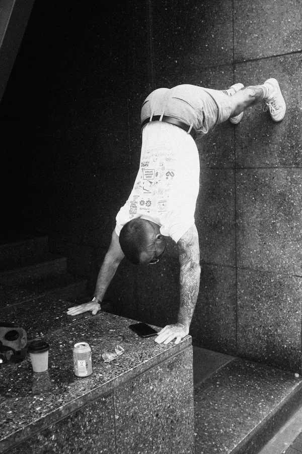 Man does a handstand against a dark stone wall, black and white, flash by Kilian Amrehn