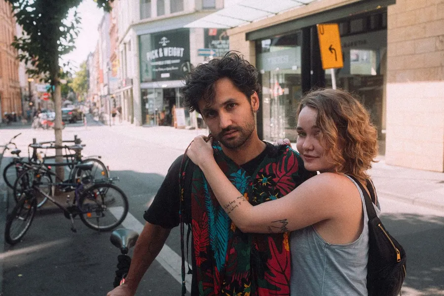 Couple hugging on a sunny shopping street beside parked bicycles, flash by Kilian Amrehn