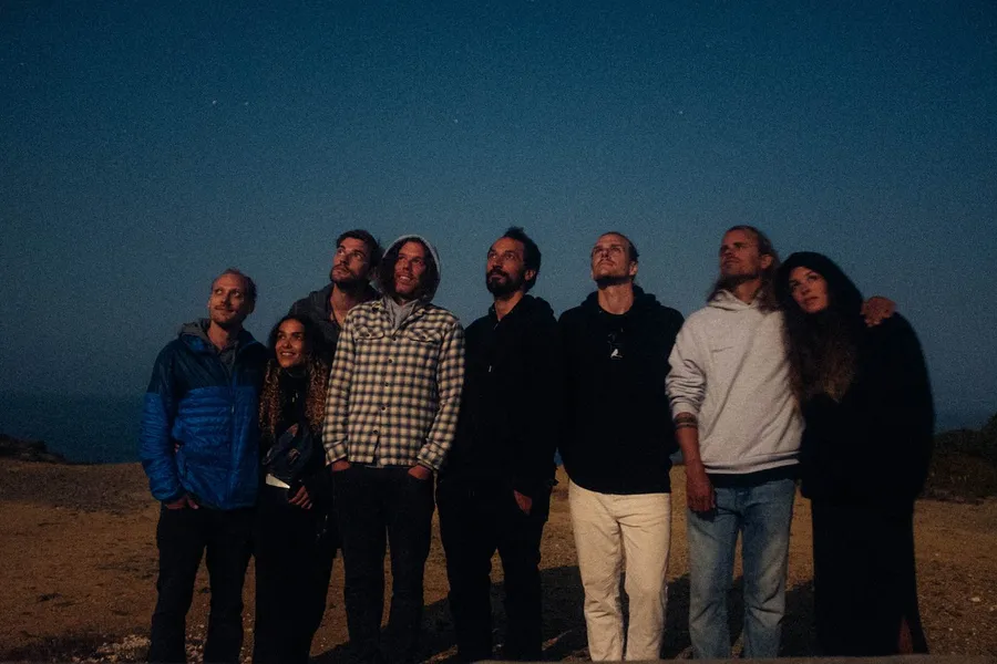 Group of friends stands on a clifftop at night gazing up at the stars, flash by Kilian Amrehn