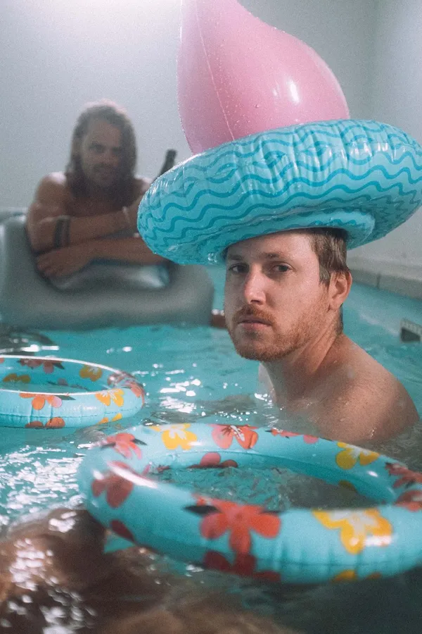 Men in an indoor pool, one wearing an inflatable hat, Denmark, flash by Kilian Amrehn