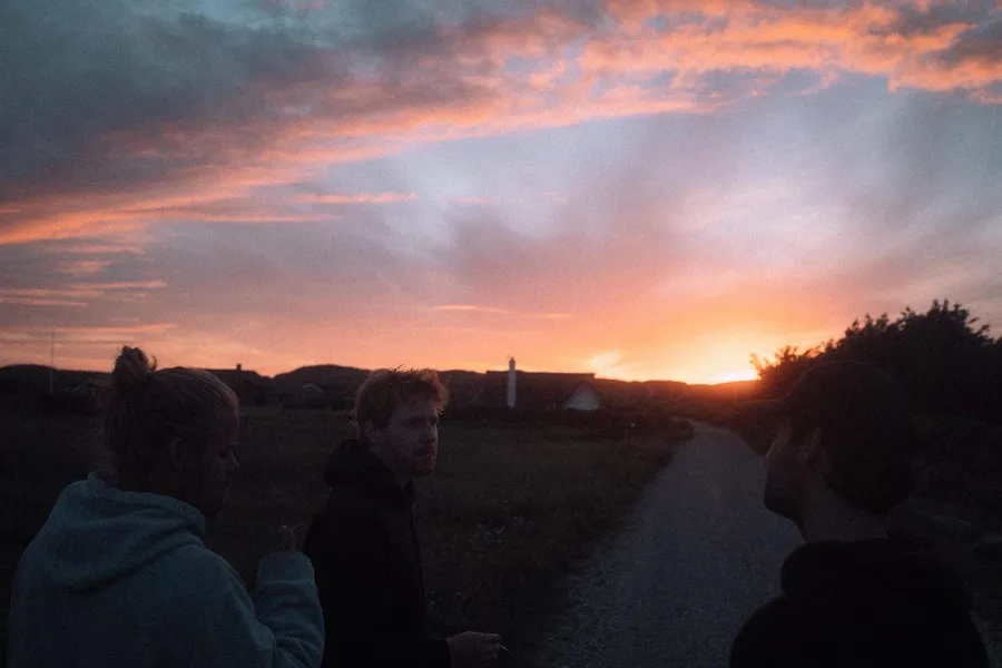Friends in silhouette on a path under a glowing sunset, Denmark, flash by Kilian Amrehn