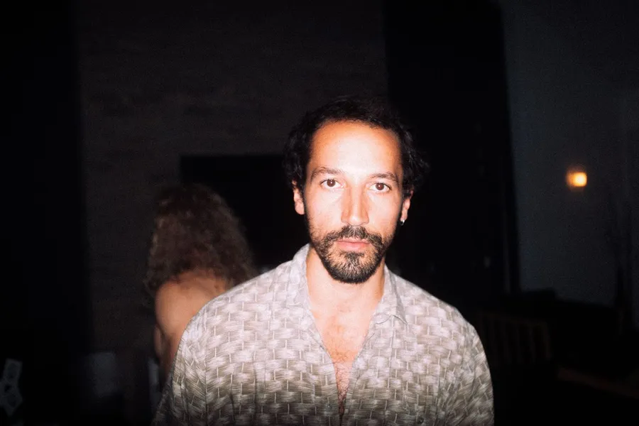 Bearded man in a patterned shirt under flash in a dark room, Denmark, flash by Kilian Amrehn