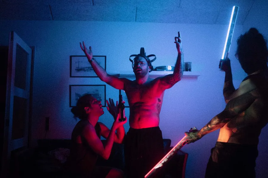 Partygoers with light sticks and raised arms in blue and red, Denmark, flash by Kilian Amrehn