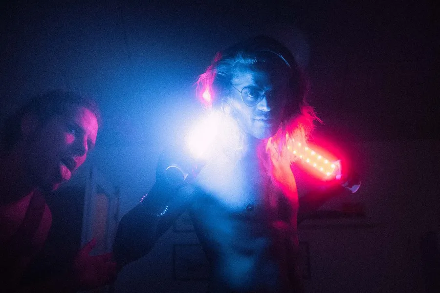 Two friends in bright blue and pink LED light in a dark room, Denmark, flash by Kilian Amrehn