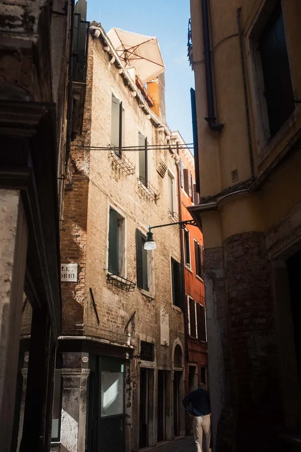 Narrow old town alley with weathered facades and a thin strip of sky, flash by Kilian Amrehn