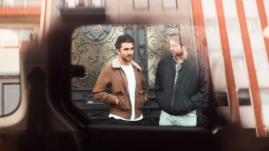 Two men before an ornate front door, shot through a car window, flash by Kilian Amrehn