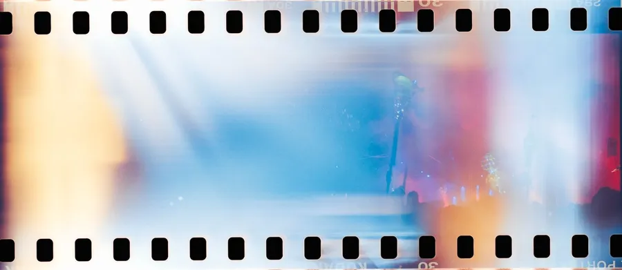 Analogue film strip with sprocket holes, light leaked in blue, red and yellow, flash by Kilian Amrehn