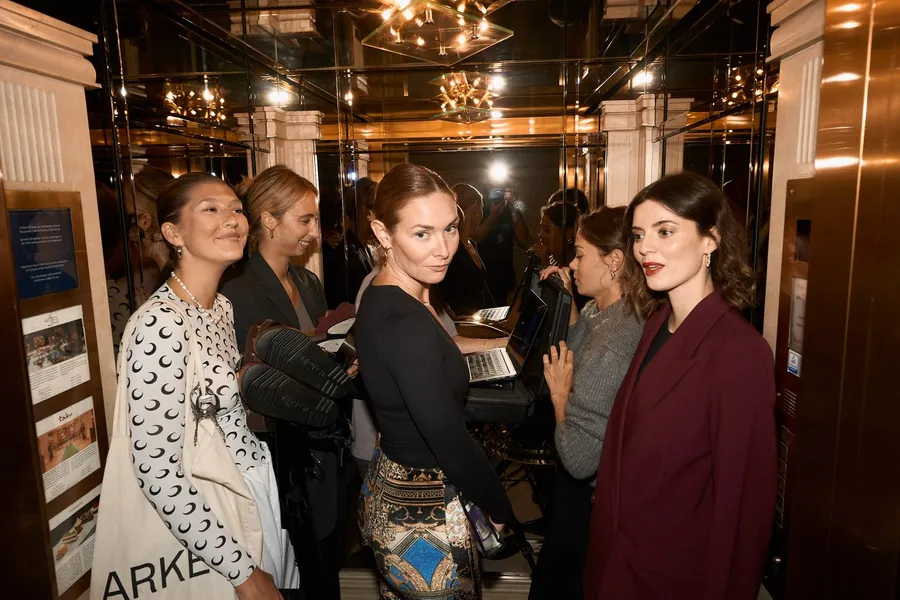 Guests in a mirrored lift with chandeliers at a Scholl event, flash by Kilian Amrehn