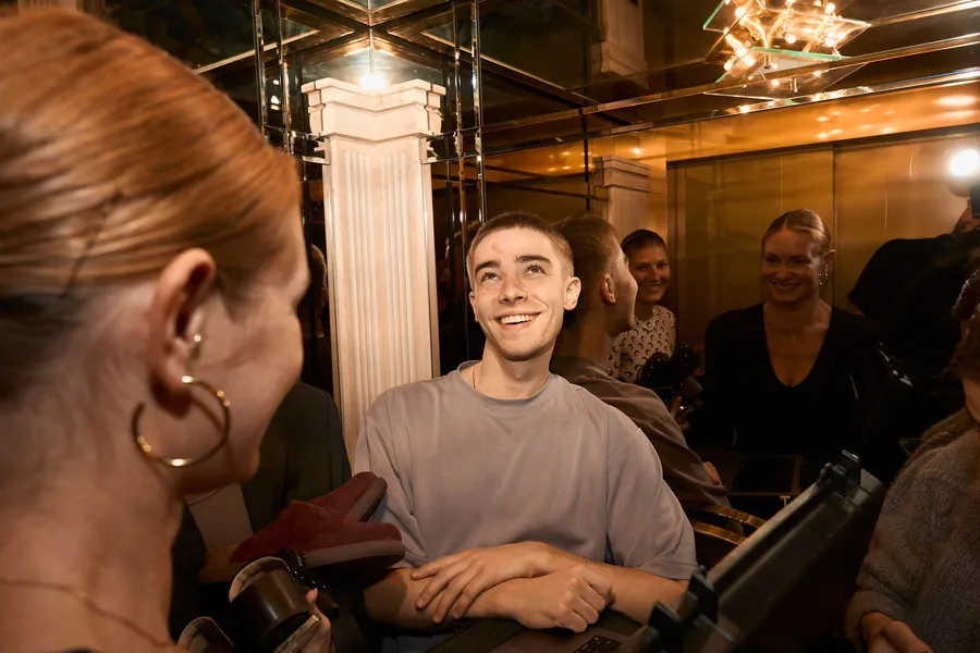 Smiling young man among guests in golden light at the Scholl event, flash by Kilian Amrehn