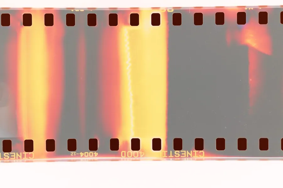 Exposed film strip with sprocket holes in orange, yellow and grey, analogue, flash by Kilian Amrehn