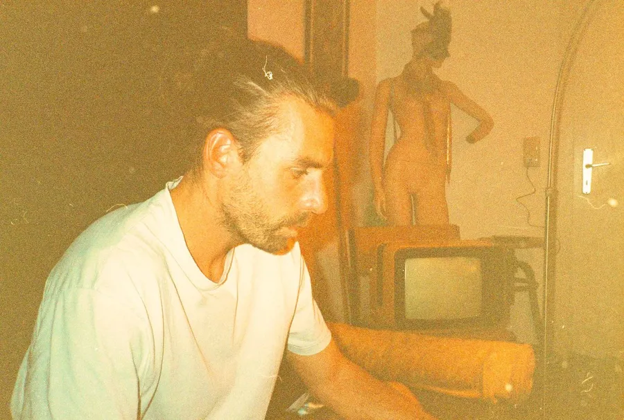 Man in a white T-shirt before an old TV set and a mannequin, analogue, flash by Kilian Amrehn