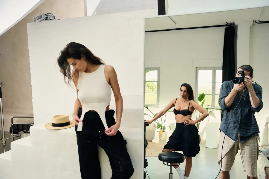 Diptych: woman in a white top on white steps, beside it a backstage view of a photographer in a bright studio, flash by Kilian Amrehn