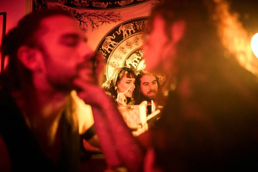 Close-up in red candlelight, two smiling faces reflected in a mirror behind, house party, flash by Kilian Amrehn