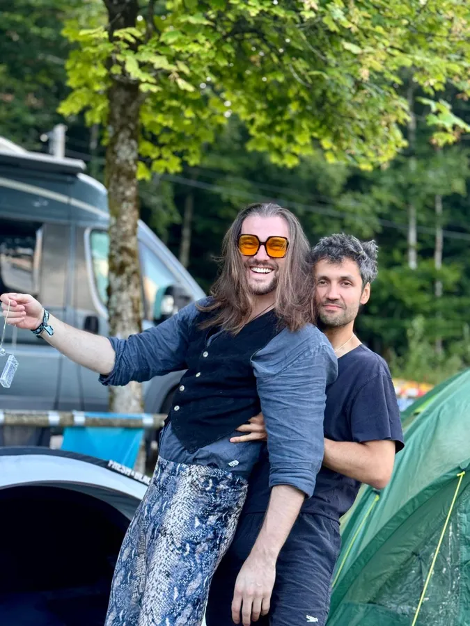 Two men fooling around at a campsite between van and tent, orange sunglasses, flash by Kilian Amrehn