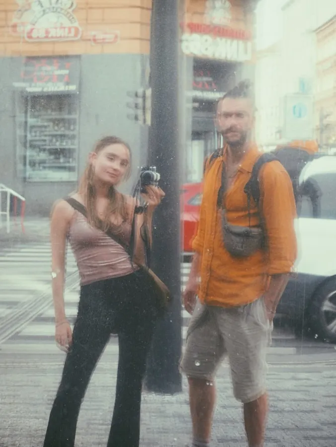 Analogue with dust and scratches: woman and man with a camera on a street corner, flash by Kilian Amrehn