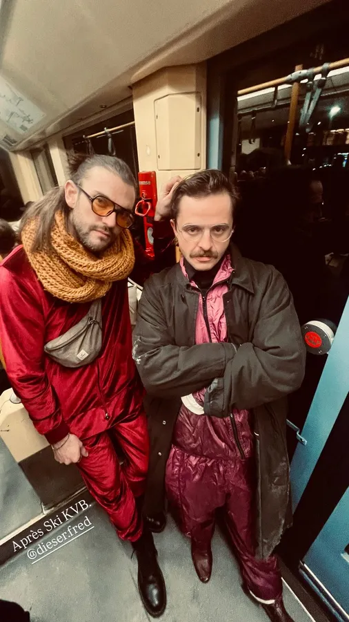 Two men in a red suit and leather coat posing in a tram, flash by Kilian Amrehn
