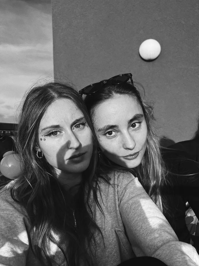 Black and white: selfie of two women, head to head, sunglasses in hair, flash by Kilian Amrehn