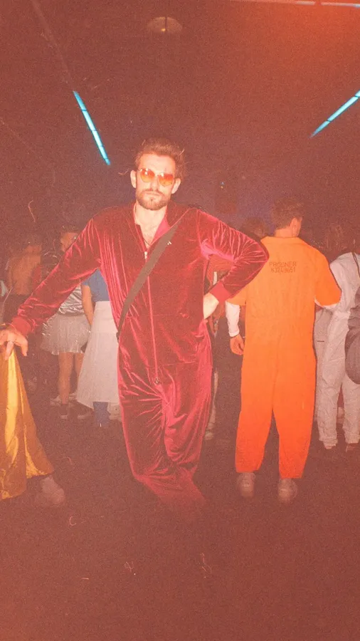 Analogue: man in a red velvet jumpsuit at a party, laser beams and reddish cast, flash by Kilian Amrehn