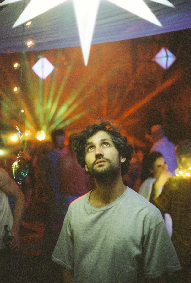 Analogue: man looking up in a club, colourful light beams and mirrored decor, flash by Kilian Amrehn