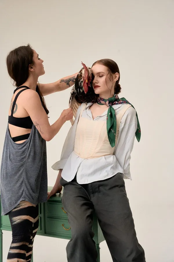 Stylist tying a silk scarf on a model, bright studio background, flash by Kilian Amrehn
