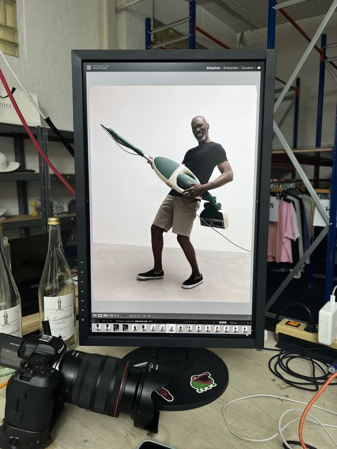 Monitor on set showing a man with a vacuum cleaner, camera and cables in front, flash by Kilian Amrehn