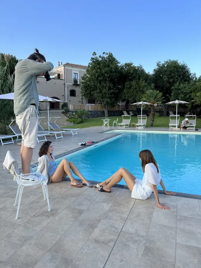 Pool shoot: photographer on a chair, two women at the pool edge in evening light, flash by Kilian Amrehn