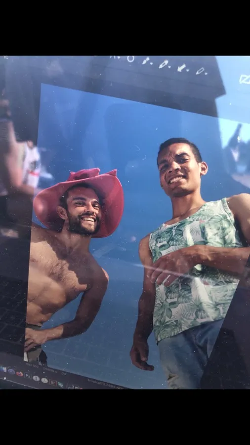 Screen showing two laughing men by a pool, one in a pink cowboy hat, flash by Kilian Amrehn