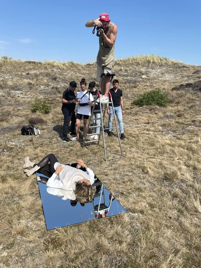 Shoot in the dunes: photographer on a ladder, model lying on a mirror, flash by Kilian Amrehn