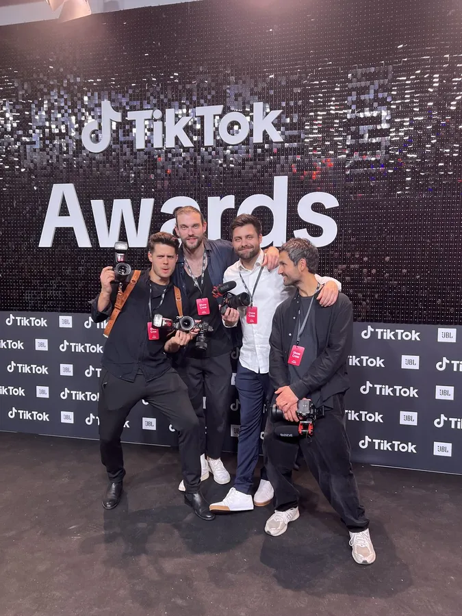 Four photographers with cameras posing in front of the TikTok Awards wall, flash by Kilian Amrehn