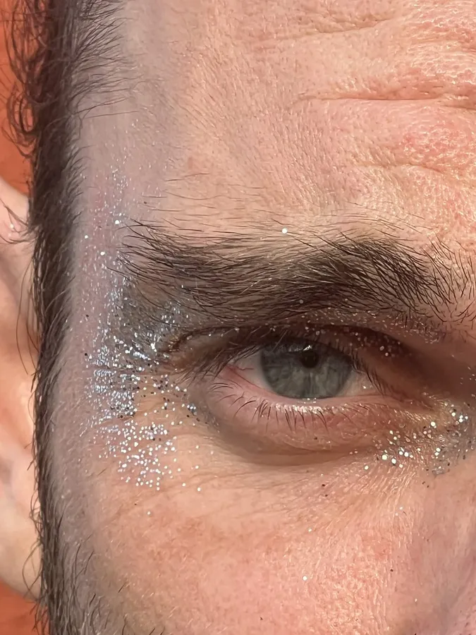 Macro of a grey-green eye with silver glitter on the skin, flash by Kilian Amrehn