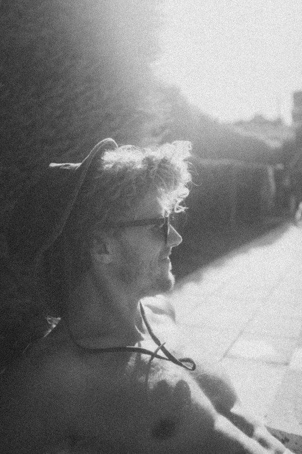 Black and white against the light: man with hat and curly hair in profile, flash by Kilian Amrehn
