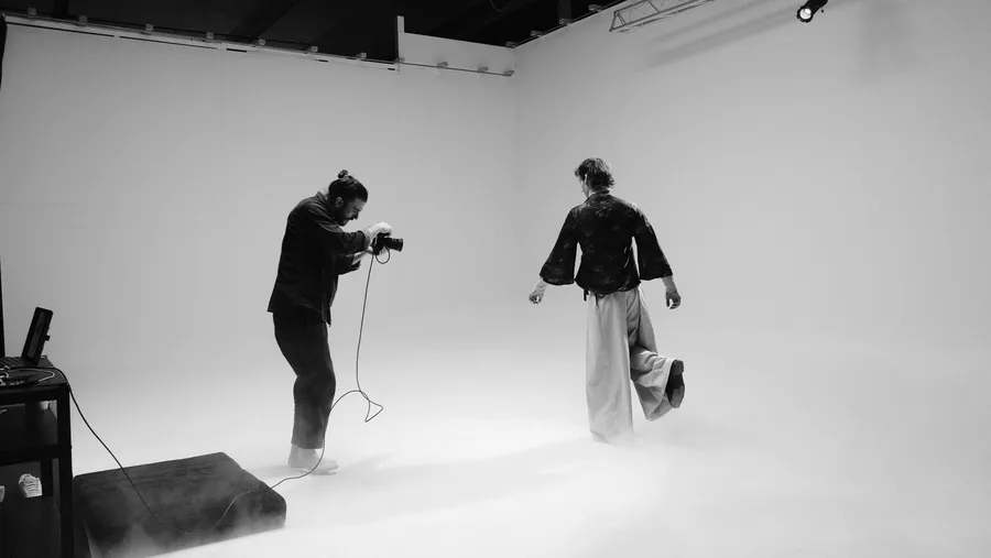 Black and white: photographer and model in fog in a white studio cove, flash by Kilian Amrehn