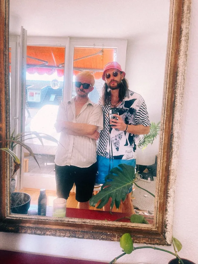 Two men in sunglasses in a large gold-framed mirror, flash by Kilian Amrehn