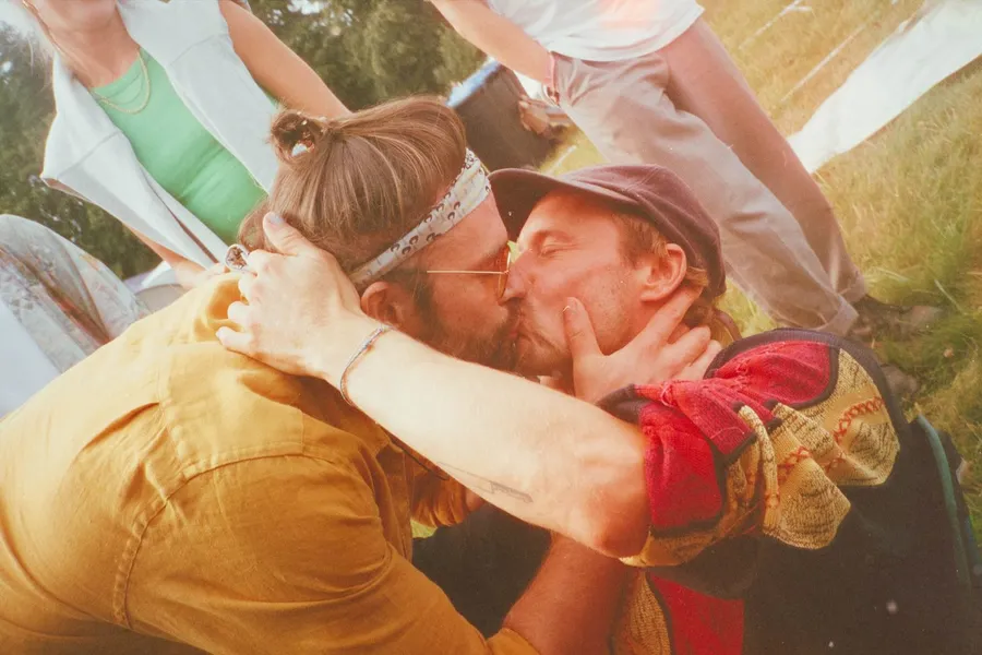 Analogue in warm tones: two men kissing intensely on a meadow, flash by Kilian Amrehn