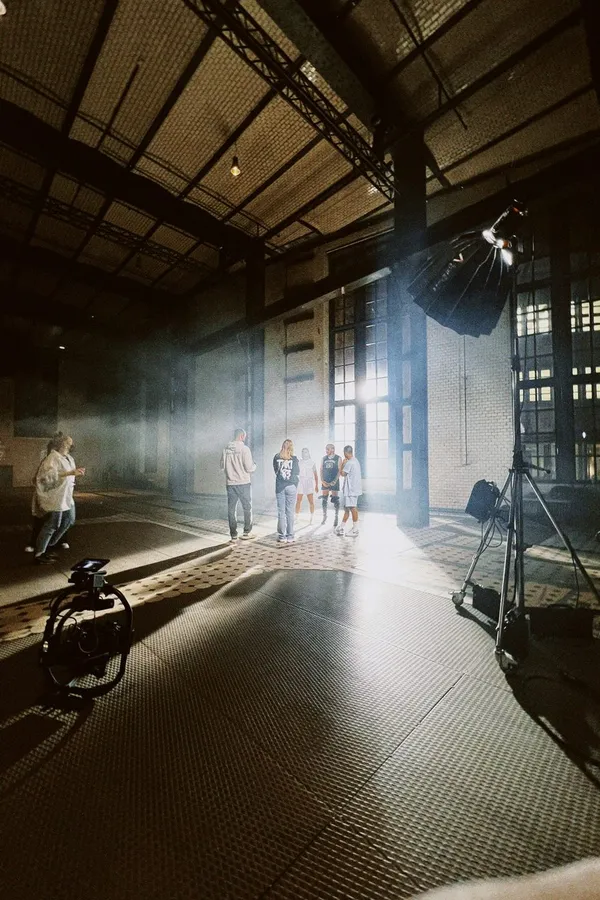 Set in an old industrial hall, light beams falling through tall windows, flash by Kilian Amrehn