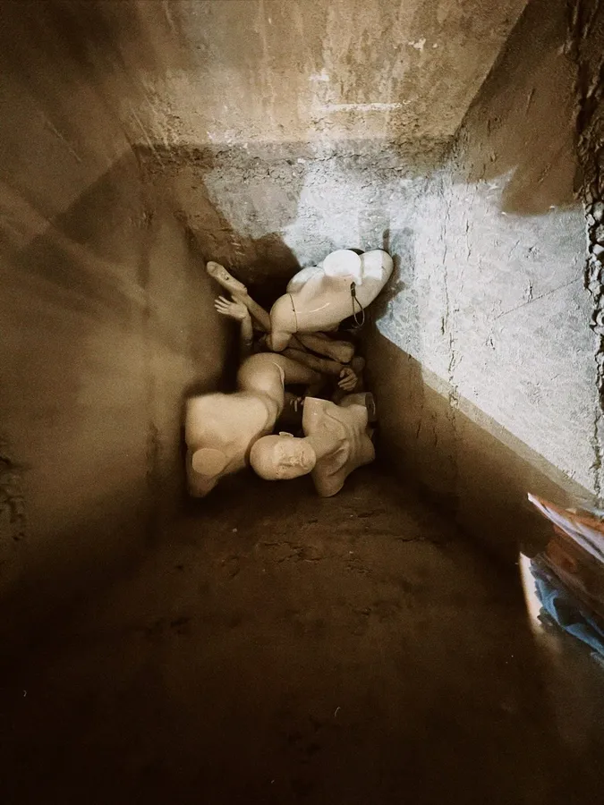 Top-down view into a shaft full of pale mannequin parts, flash by Kilian Amrehn