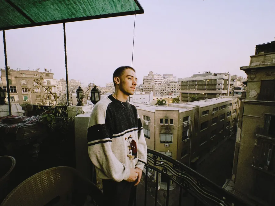 Young man on a rooftop terrace above the city in evening light, flash by Kilian Amrehn
