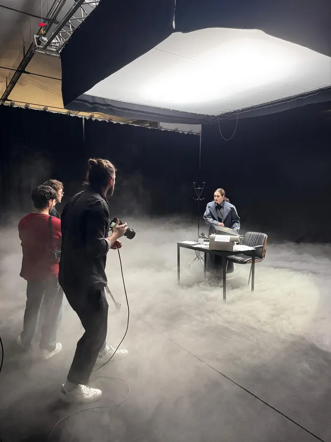 Backstage in fog: camera crew filming a man at a desk under a softbox, flash by Kilian Amrehn
